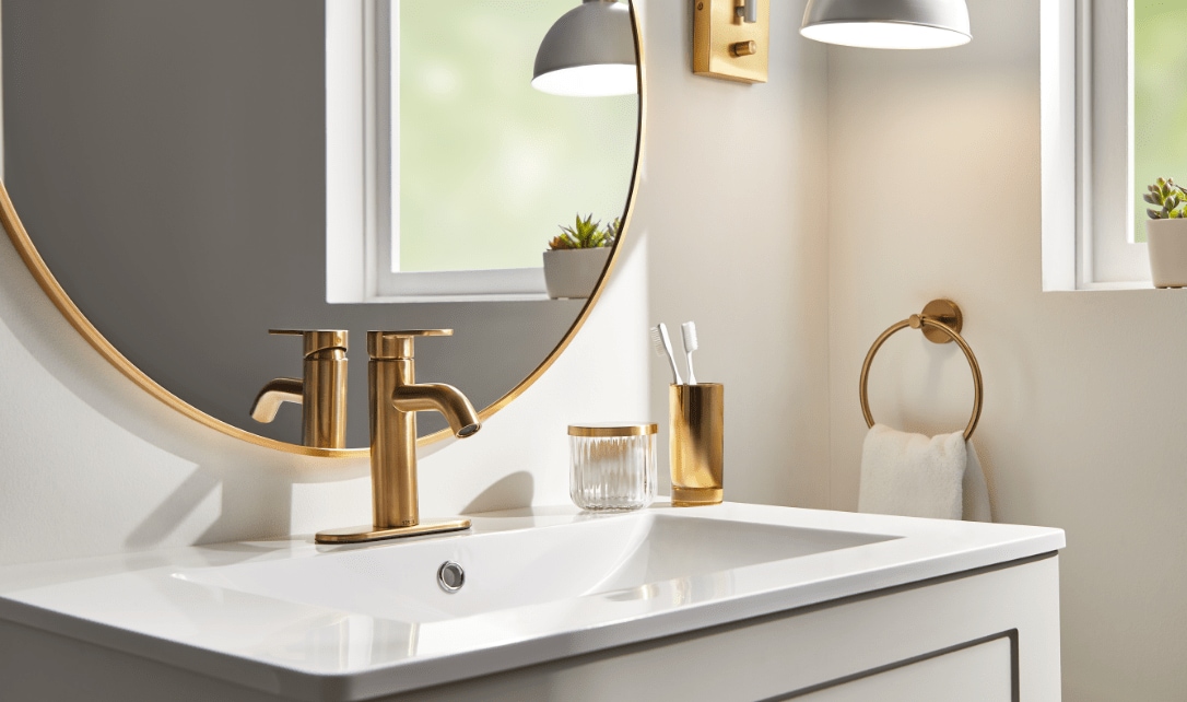 Gros plan sur un lavabo de salle de bain équipé d'un robinet moderne en or, d'un miroir rond et d'un décor élégant.
