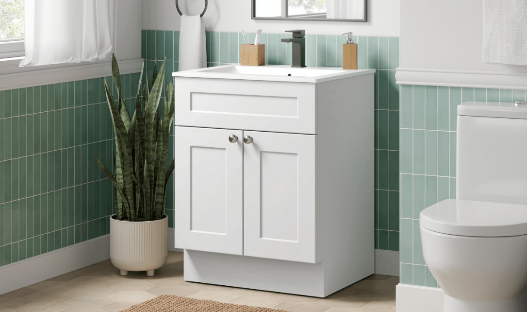 Une salle de bain dotée d'un meuble-lavabo blanc à un seul lavabo, de murs carrelés en vert et de toilettes modernes.