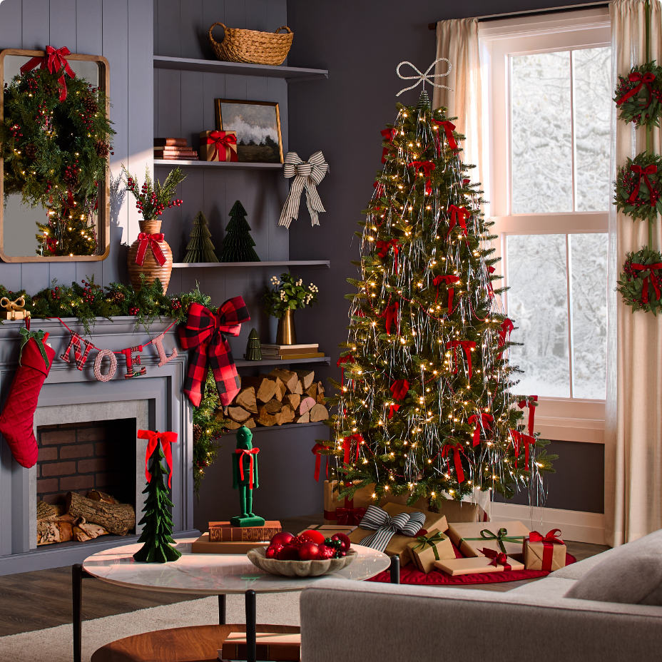 Un salon décoré d’un sapin de Noël et d’un éventail de nœuds et de rubans rouges.