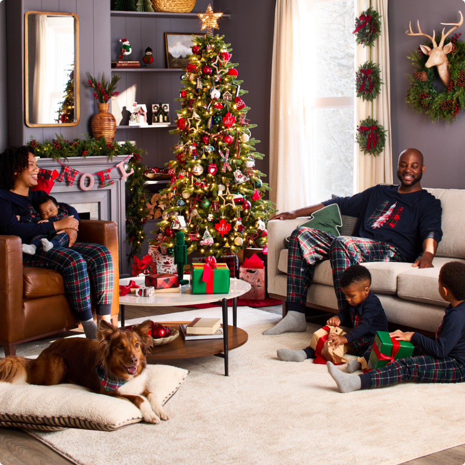 Une famille vêtue de pyjamas assortis qui se détend dans un salon décoré pour Noël.
