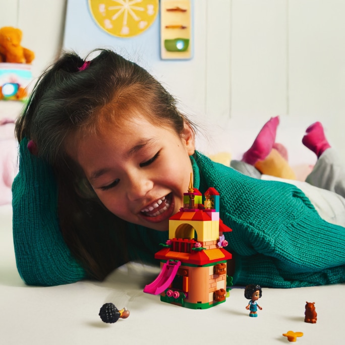 Un enfant qui joue avec des jouets et des jeux sur le thème des Fêtes dans une pièce lumineuse.