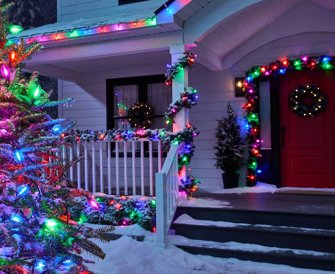 Une maison la nuit, décorée de guirlandes lumineuses colorées NOMA Big & Bright.