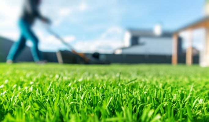 Person mowing a well-maintained, lush green lawn.