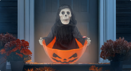 A grim reaper decoration sitting in an orange candy bowl.