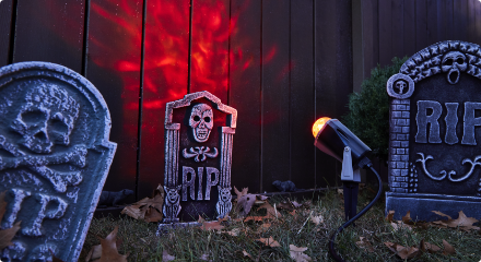 Outdoor Halloween graveyard decorations with tombstones and eerie lighting.