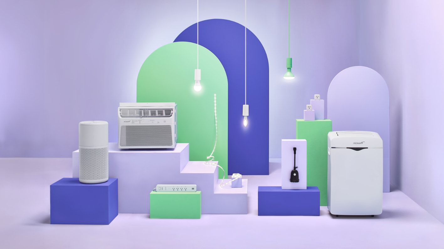 Various NOMA iQ home appliances displayed on colorful geometric platforms with hanging lights in the background.