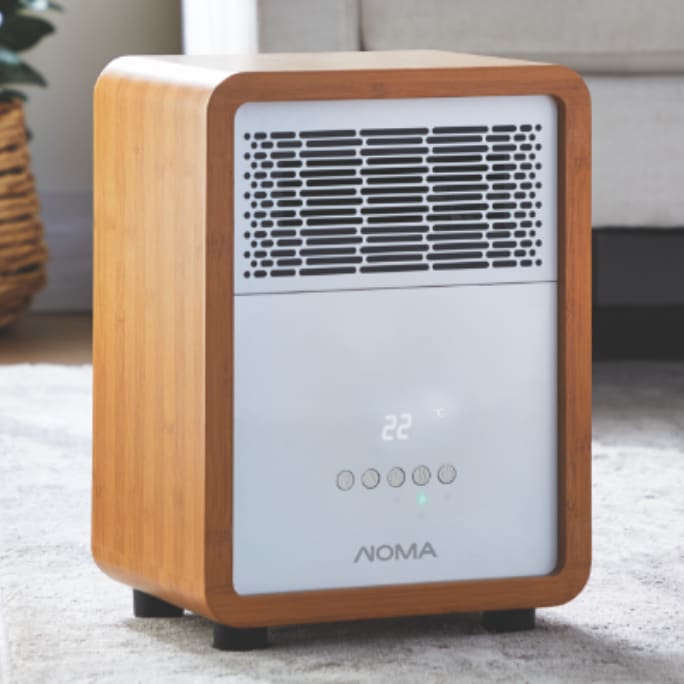 A NOMA air purifier with a wooden exterior stands on a carpeted floor in a living room.