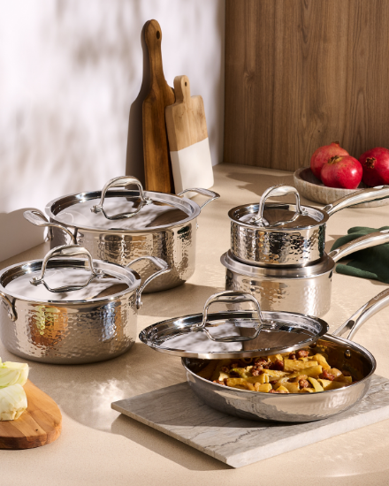 Assortiment de casseroles et de poêles de cuisine présentés sur un comptoir avec des ustensiles de cuisson.
