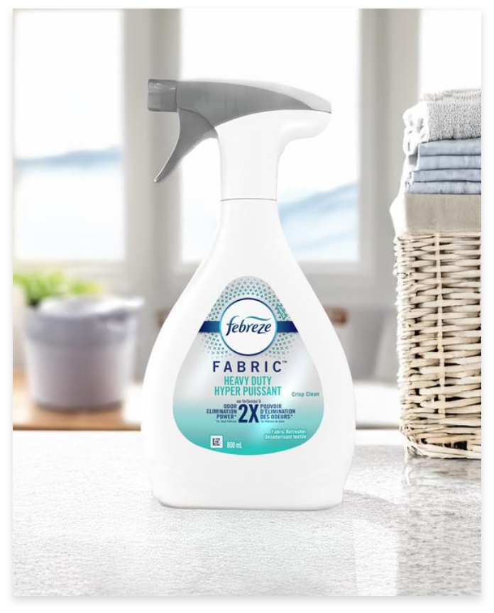 A bottle of Febreze Fabric Refresher on a countertop next to a laundry basket.
