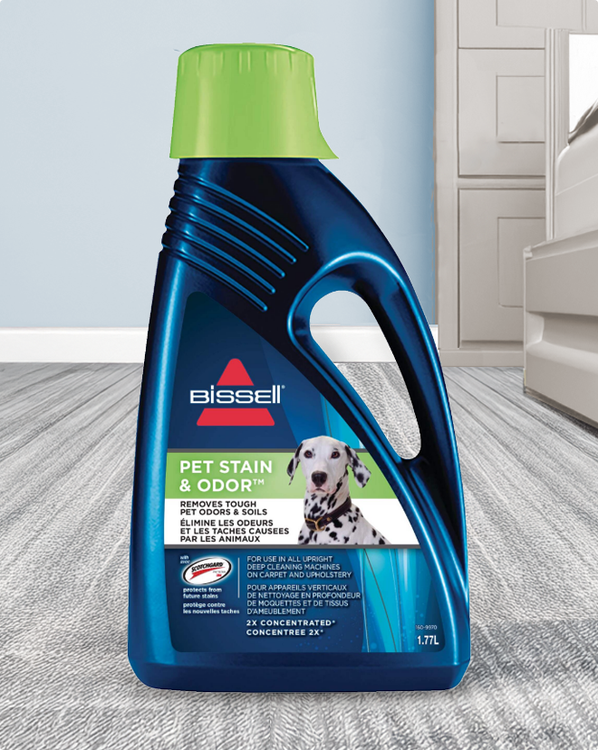 A bottle of BISSELL Pet Stain & Odor cleaner on a carpeted floor.