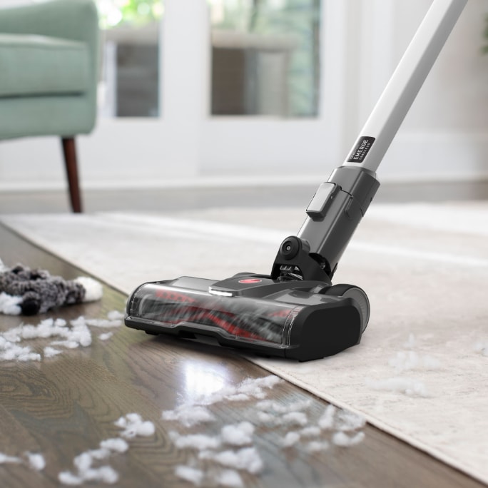 Vacuum cleaner being used on a hardwood floor to clean dust and debris.