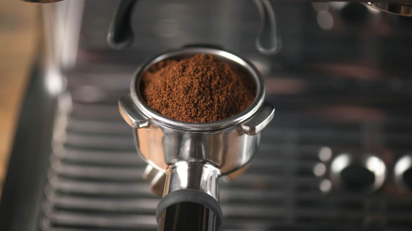 Portafilter filled with ground coffee in an espresso machine. Text reads "Ground Coffee" and includes a "Shop Now" button.