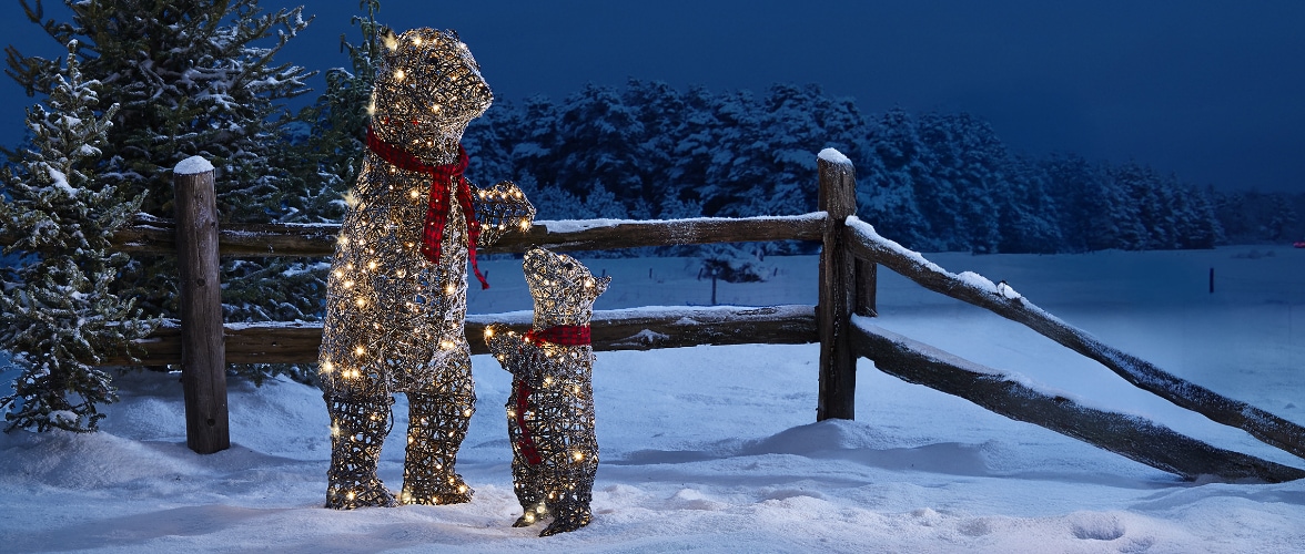 Light-up mother bear and cub decorations  standing in a snowy outdoor setting next to a wooden fence.