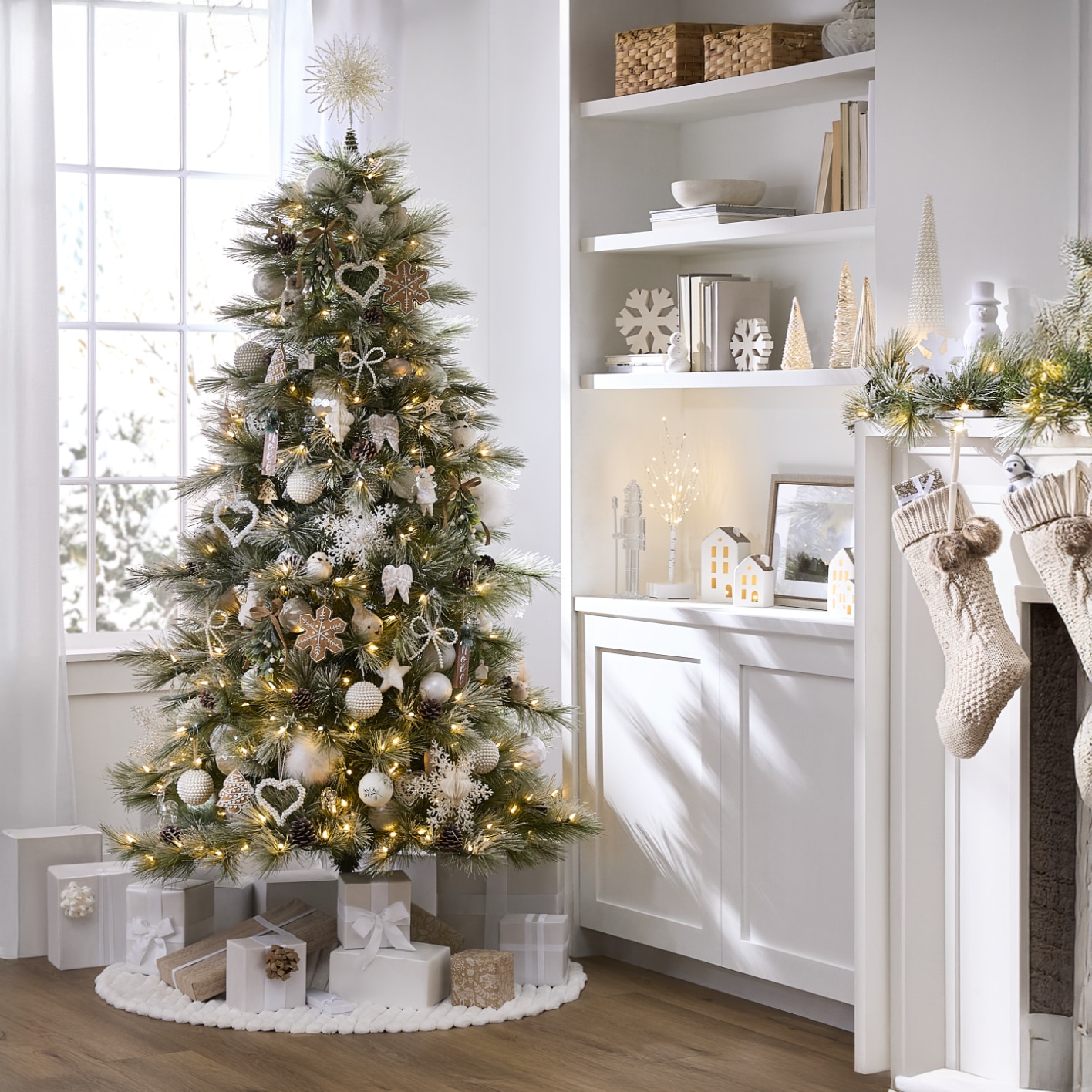 Living room with a decorated Christmas tree, stockings on the fireplace, and festive decorations on shelves and mantel.