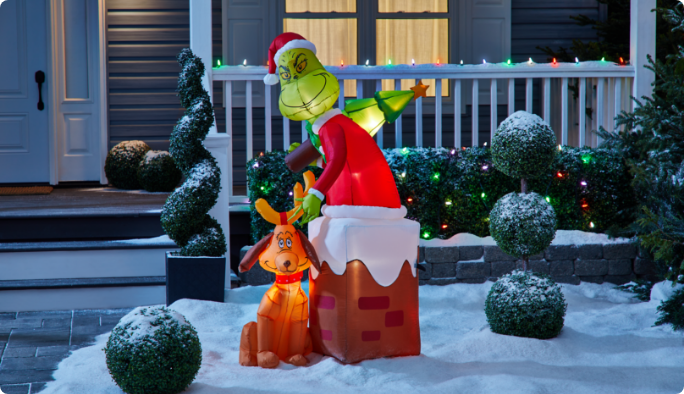 Décoration gonflable Airblown du Grincheux dans la cheminée dans une cour enneigée.