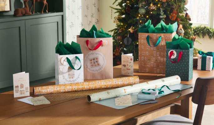Festive gift wrap and holiday decorations on a wooden table.