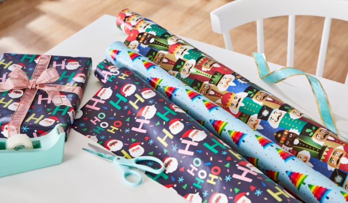 Festive wrapping paper rolls with holiday designs on a table.