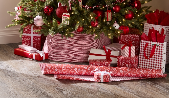 A variety of red, white, and green wrapped gifts beneath a Christmas tree.