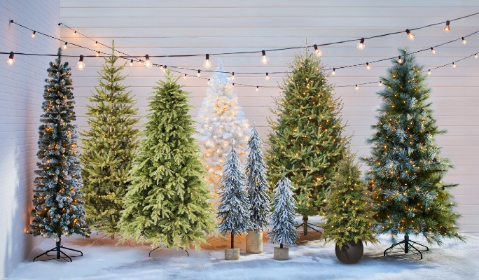 Une rangée d’arbres de Noël artificiels de styles et de tailles variés.