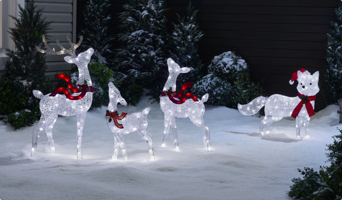 A range of CANVAS Arctic White pre-lit wireform figures on a snowy lawn