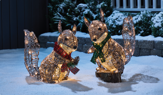 A range of CANVAS Canadian Cabin  pre-lit wireforms on a snowy lawn