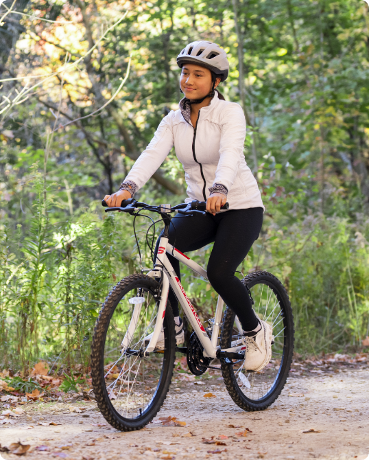 A person wearing a helmet rides a  Supercycle Reaction Hardtail Mountain Bike on a forest trail. 