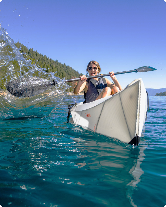 A person kayaking on a clear blue lake.