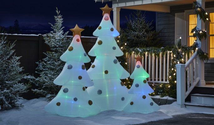 A house with NOMA Advanced Smart inflatable trees and a glowing snowman in the yard with wreaths, garlands, and snow on the ground.