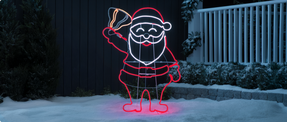 Neon decoration of Santa Claus holding a bell, displayed in a snowy yard by a house.