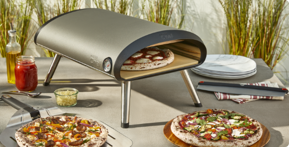 A MASTER Chef Gas Pizza Oven on a table with two cooked pizzas.