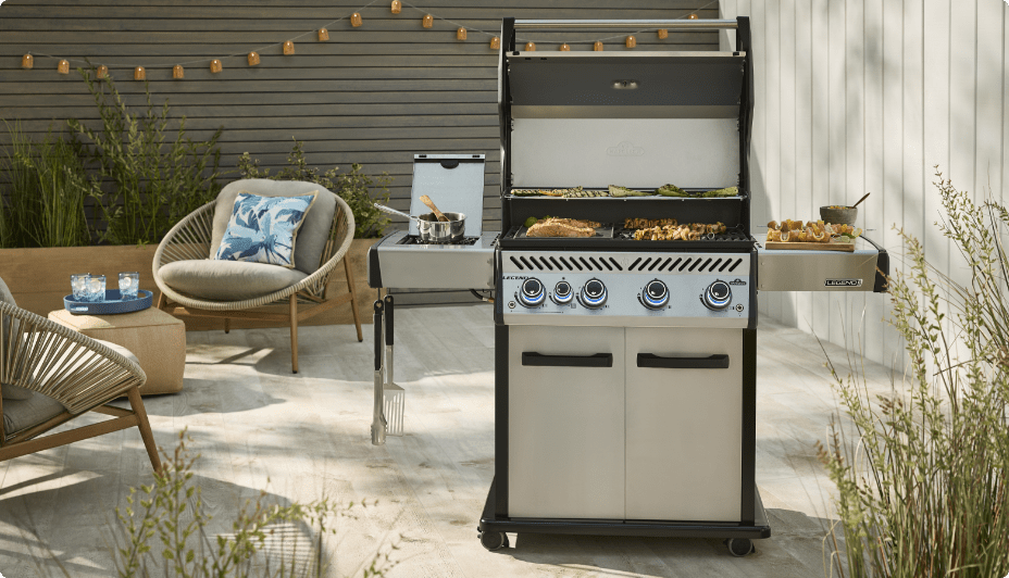 A Napoleon Legend Pro 4-Burner BBQ cooking foods on a patio in front of various patio furniture.