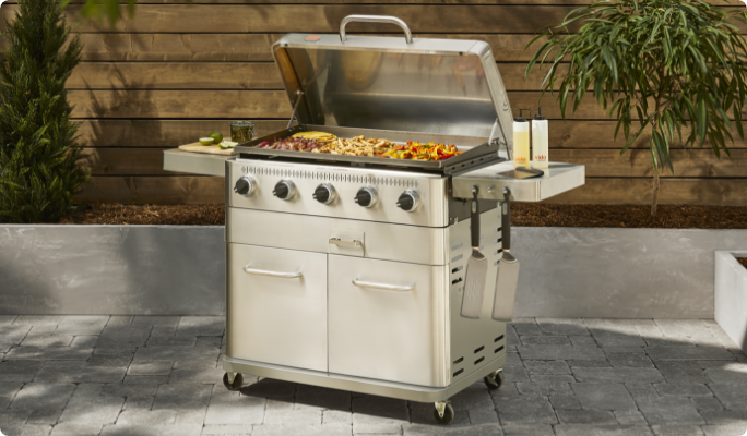 A Vida by PADERNO 5-Burner Griddle cooking food on a patio.