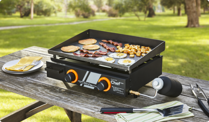 A MASTER Chef® Grill Turismo 2-Burner Tabletop Griddle sitting on a table, cooking food outside.