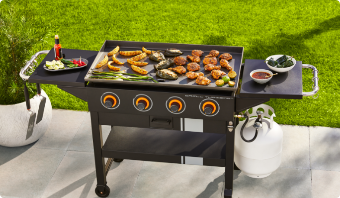A MASTER Chef® Grill Turismo 4-Burner Griddle cooking food in a yard.