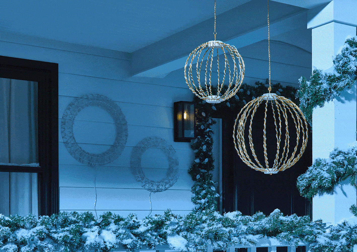 Diverses décorations lumineuses scintillantes présentées sur un porche enneigé. 