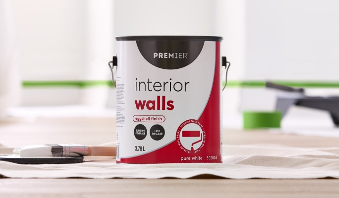 A 3.78-L bag of concrete-coloured Premier Ready to Roll Interior Wall Paint is poured into a paint tray.