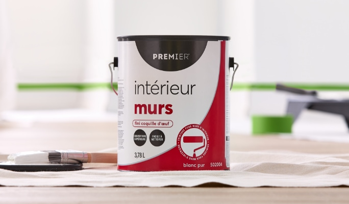 Un sac de 3,78 litres de peinture murale intérieure Premier Ready to Roll de couleur béton est versé dans un bac à peinture.