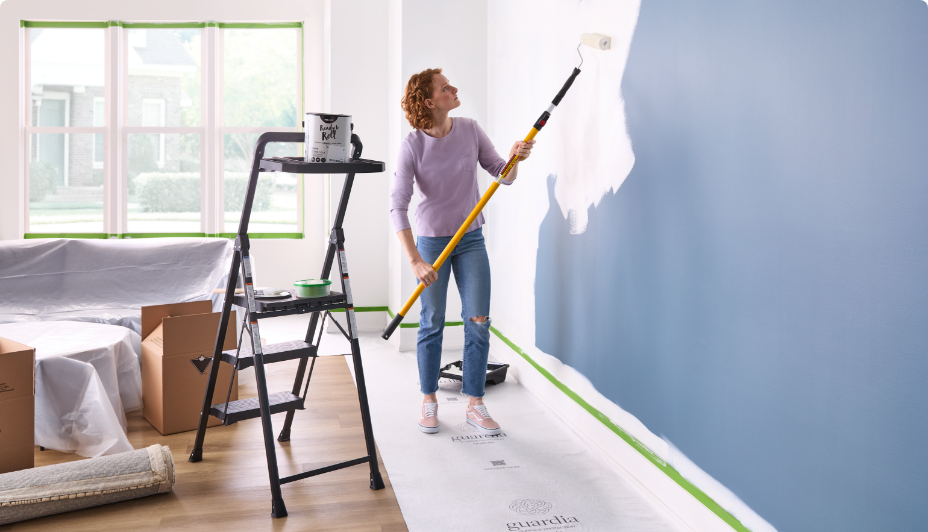 Person repainting a blue wall white.