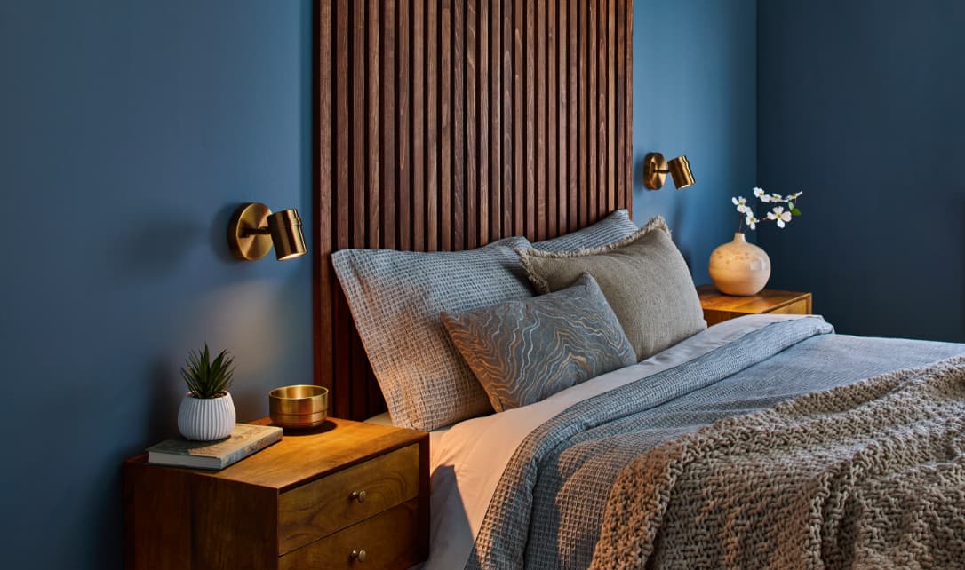 Stylish bedroom with blue walls and a wooden headboard.