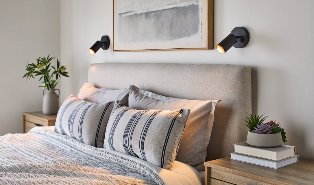 Cozy bedroom with a neatly made bed and wall-mounted reading lights.