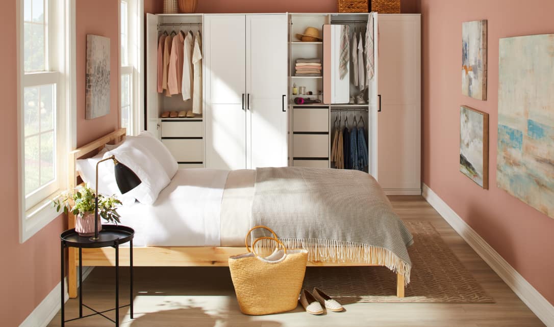 Cozy bedroom with pink walls and open closet shelving system.