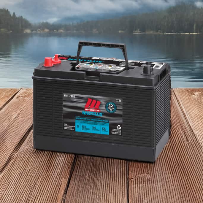 A marine battery placed on a wooden dock near a lake or river.