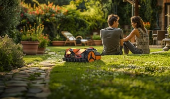 Small orange and black Worx robotic lawn mower working