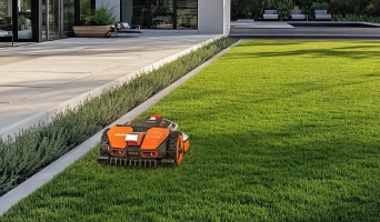 An Worx orange and black robotic lawn mower cutting grass on a well-kept lawn
