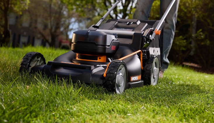 Personne poussant une tondeuse à gazon électrique Worx. La tondeuse a un sac de ramassage à l’arrière.