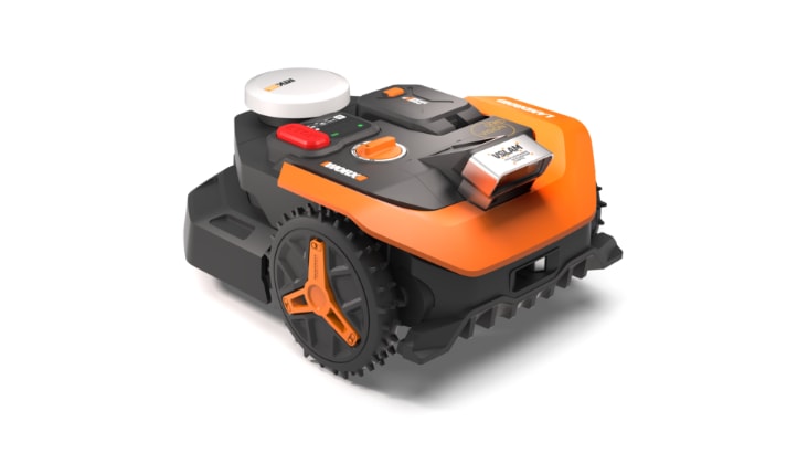 An Worx orange and black robotic lawn mower cutting grass on a well-kept lawn