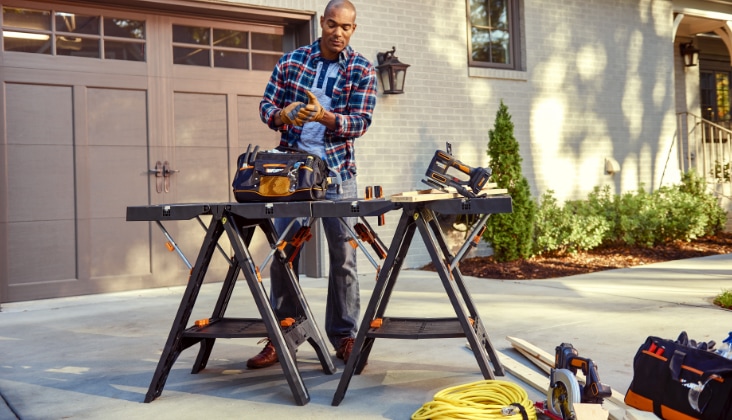 Un homme utilise une perceuse électrique sur un établi à l’extérieur