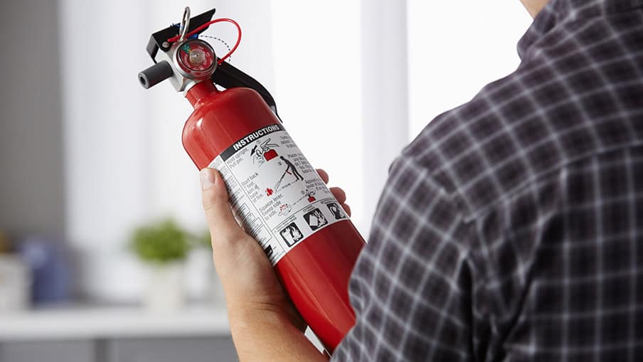 Person reading instructions on fire extinguisher label 
