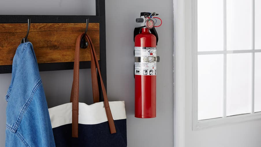 Fire extinguisher mounted on wall next to coat rack 