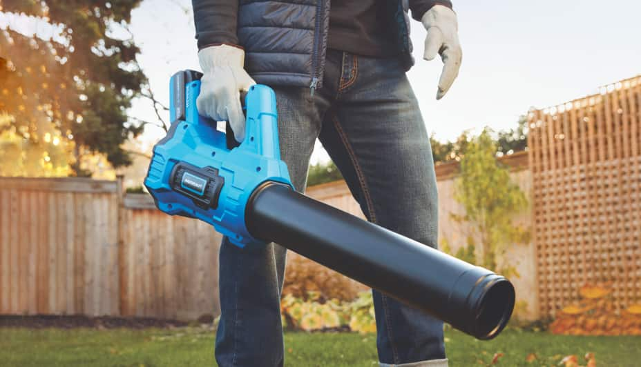 A man blows uses a Mastercraft 20V Brushless Leaf Blower to clear leaves in a backyard.